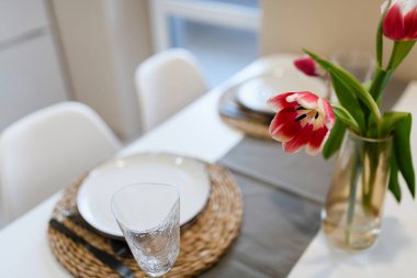 Mutfakta tabakları ve çiçekleri olan yeni parlak bir masa.