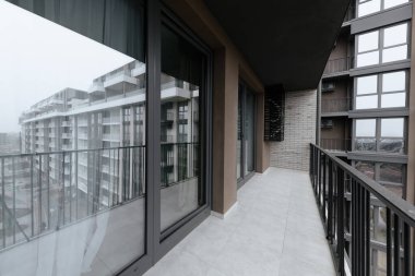 Yeni, temiz bir balkon. Bir apartmanda geniş pencereler var.