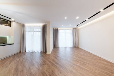 Geniş pencereleri ve beyaz duvarları olan büyük, parlak bir stüdyo mutfağı vardı.