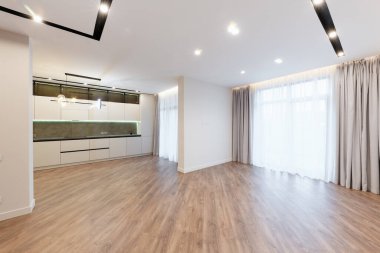 Geniş pencereleri ve beyaz duvarları olan büyük, parlak bir stüdyo mutfağı vardı.