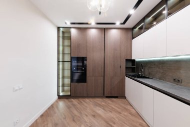 Beyaz ve koyu cepheli ve ışıklandırmalı yeni şık mutfak.