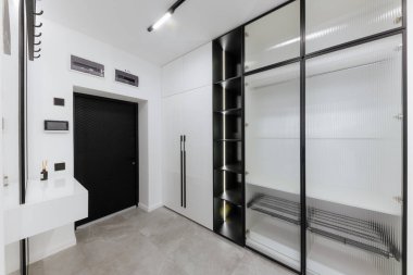 Giysileri ve karanlık rafları olan yeni bir evde şık ve modern parlak bir koridor.