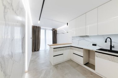 Geniş pencereli ve ışıklandırmalı parlak bir Stüdyo mutfağının iç tasarımı