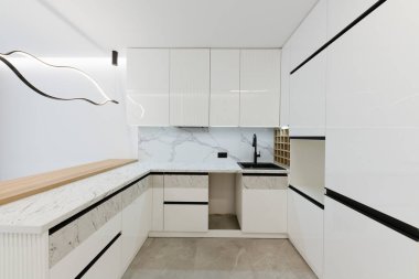 Beyaz mobilya ve ışıklandırmalı yeni parlak stüdyo mutfağı