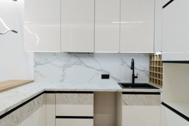 Beyaz mobilya ve ışıklandırmalı yeni parlak stüdyo mutfağı