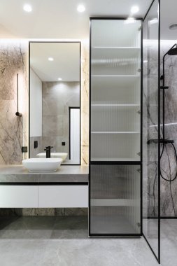 Banyo içi gri fayanslar, ayna ve ışıklandırmayla dolu. dikey resim