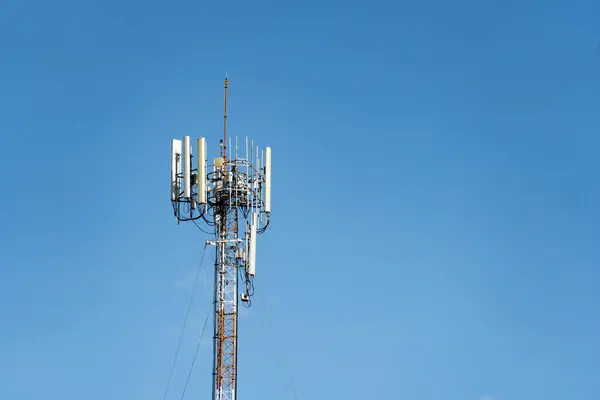 stock image Telecommunications tower with multiple antennas and dishes against a clear blue sky,providing wireless network connectivity and data transmission for mobile devices,internet,and communications.