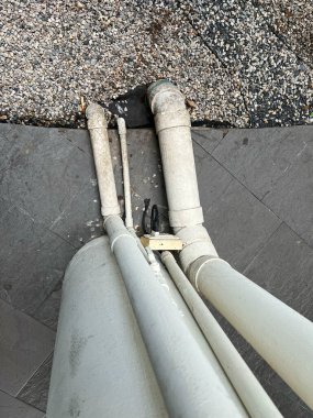 Asfaltlı kentsel çevreye yerleştirilmiş beton boruların ve tesisat altyapısının yakın görüntüsü.