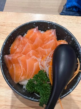 Ahşap bir yemek masasında servis edilen süslü maydanozlu güzel hazırlanmış Sashimi Dilimleri.