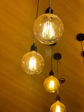 Konforlu ve modern iç mekan dekorunda sıcak, parıltılı ve ortam aydınlatma çözeltisi sağlayan birden fazla asılı ampullü zarif cam avize..