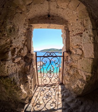 Adadaki tropik körfez Kale harabe penceresinden görünüyor