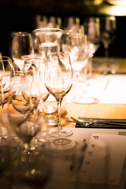 Şarap kadehleri karamsar ışıklarla dolu bir masada tadımlık..