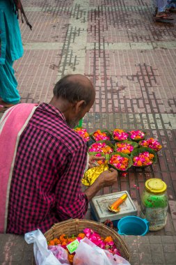 8 Temmuz 2022 Haridwar India. Hindu ayinleri için Ganj nehrinin kıyısında ya da ghatlarında renkli çiçekler satan bir adam..