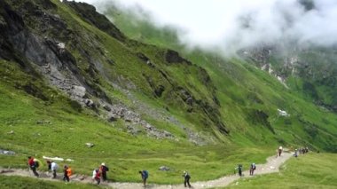 14 Temmuz 2022, Himachal Pradesh Hindistan. Sırt çantalı ve bastonlu insanlar, Himalayalar 'da Shrikhand Mahadev Kailash Yatra sırasında yürüyüş yapıyorlar..