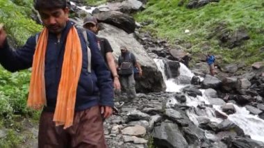 14 Temmuz 2022, Himachal Pradesh Hindistan. Sırt çantalı ve bastonlu insanlar, Himalayalar 'da Shrikhand Mahadev Kailash Yatra sırasında yürüyüş yapıyorlar..