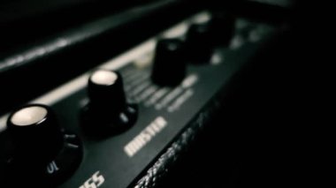 Siyah bir gitar amplifikatörünün sinematik görüntüsü. Üçlü, bas düğmeleri. Hindistan