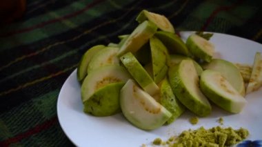 Hint baharatlarıyla servis edilen yakın plan guava salatası. Beyaz tabakta yeşil tuz..
