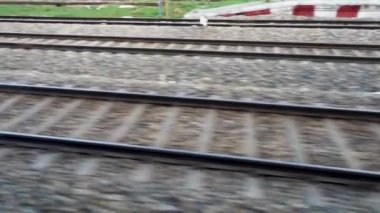 Ağaçlar ve elektrik direkleriyle hızlı giden bir tren boyunca paralel raylar. Kuzey Hindistan Demiryolları. Hindistan.