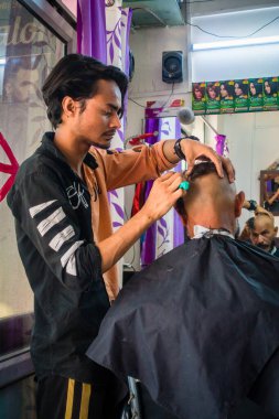 14 Ekim 2022 Uttarakhand, Hindistan. Geleneksel kel saç kesimine maruz kalan Hintli bir adam. Kültürel uygulamalara göre küçük at kuyruklu bir adam. Hint geleneğini ve kültürünü kutluyoruz..