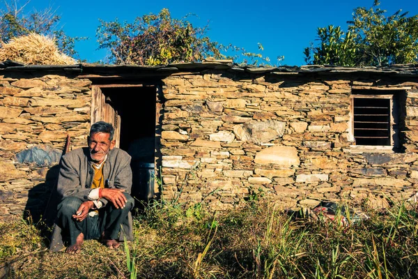 14 Ekim 2022 Uttarakhand, Hindistan. Garhwal, Uttarakhand 'daki yerli bir adamın portresi. Geleneksel kayadan yapılmış çamur evinin dışında oturuyor..