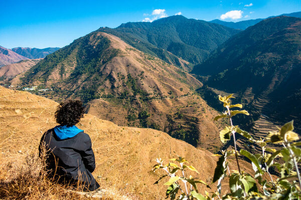 October 14th 2022, Uttarakhand India. Lone man with flowing hair, savoring the breathtaking Himalayan Mountain scenery. Serene moment amid nature.