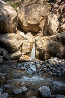 Manzaralı Himalaya şelalesi Himachal Pradesh, Hindistan 'daki devasa kayaların arasında. Kinner Kailash Yatra 'nın bir parçası, bir Hindu haccı..