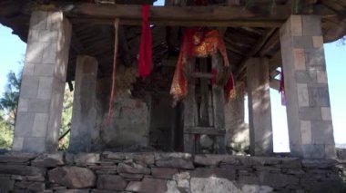 Uttarakhand, Hindistan 'da kutsal taşlarla süslenmiş yıpranmış eski bir tapınağın içini keşfediyorum.