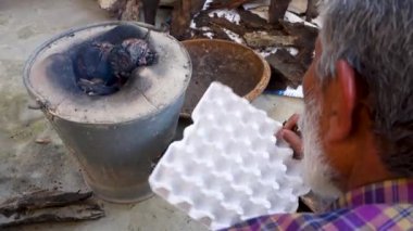 Geleneksel odun sobasında demir cımbız kullanarak patlıcan kızartmak. Uttarakhand Hindistan