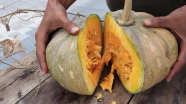 Ahşap desenli bir masanın üstünde balkabağı kütüğüyle yakın çekim. Hindistan