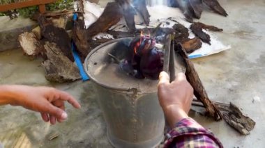 Geleneksel odun sobasında demir cımbız kullanarak patlıcan kızartmak. Uttarakhand Hindistan