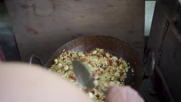 自家製のグラノーラをオート ナッツ 種子を大きな鋳鉄製の釜または伝統的なストーブの上にカダイで調製します ウッタラーカンド インディア — ストック動画