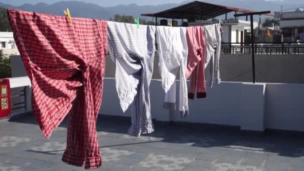 太陽の下で外で乾燥洗濯のクローズアップショット シャツは屋根の上のワイヤーにかかっている ウッタラーカンド州デフラダン市 インド — ストック動画