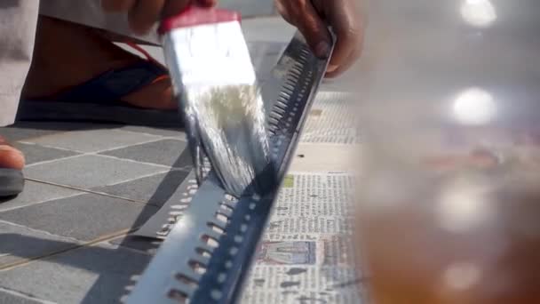 グレーペイントの表面にレッドペイントブラシを保持する手のクローズアップショット インド — ストック動画