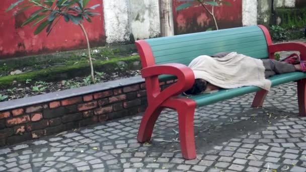 2023年12月25日 Uttarakhand India 印度Uttarakhand市Dehradun市 一个无家可归的人与毛毯睡在公园的长椅上 城市无家可归和易受伤害性的肖像 — 图库视频影像