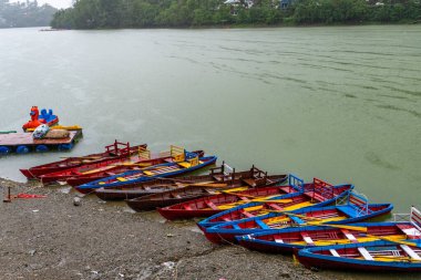 Empty boats lined up on the lakeside at Bhimtal Lake during the monsoon season, an off-season period for tourists in Almora, Uttarakhand, India. clipart