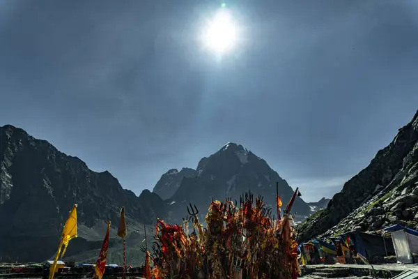 Stock image July25th2024, Himachal Pradesh, India. Religious red cloths (chunri) and tridents (trishul), symbols of Lord Shiva, against Kailash Parvat during the Mani Mahesh Kailash Yatra, a Hindu and Buddhist pilgrimage.