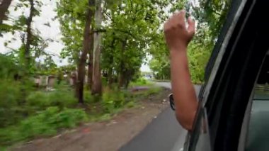 12 Temmuz 2024, Uttarakhand Hindistan. Yolculuğun tadını çıkaran bir yolcunun sinematik çekimi, hareket halindeki bir araçtan el sallaması, Uttarakhand, Hindistan 'da özgürlüğü kucaklaması..