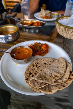 North Indian platter featuring roti, dal, and mixed vegetables served on a dining table. Healthy meal, enjoyed on the road during travel in Himachal Pradesh, India, offers a taste of local cuisine. clipart