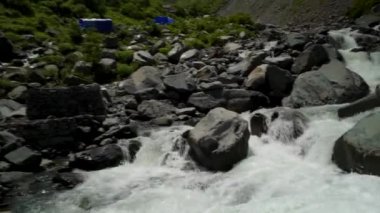 25 Temmuz 2024, Himachal Pradesh, Hindistan. Bir adam, Chamba Vadisi, Himachal Pradesh, Hindistan 'daki Kailash Manimahesh Yatra' da vahşi bir buzul nehri üzerinde derme çatma bir tahta köprüyü dikkatle geçer..