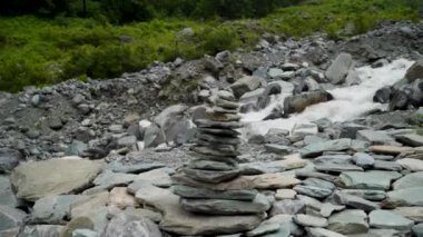 Hindistan 'ın Himachal Pradesh kentindeki Kailash Manimahesh Yatra sırasında arka planda akan bir nehir ile kayalardan ve çakıl taşlarından yapılmış kutsal Şiva Lingam' lar el değmiştir.,