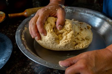 Hindistan 'ın Uttarakhand kentindeki geleneksel aşçılık uygulamalarını sergileyerek, Kuzey Hindistan' daki bir ev mutfağında Hint ekmeği (roti) yapmak için elleri un yoğurur..