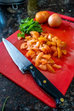 Kuzey Hindistan mutfağında domatesler ve doğranmış bıçakların olduğu masa üstü manzarası, sağlıklı köri hazırlıklarını betimliyor..