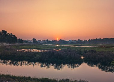 Doğu Yamuna Kanalı ve Asan Nehri, Uttarakhand, Hindistan 'ın kesişiminde yer alan turuncu gökyüzü ve geniş doğal manzarasıyla Asan Barrage, Dehradun üzerinde görkemli bir gün doğumu..