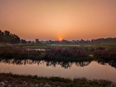 Doğu Yamuna Kanalı ve Asan Nehri, Uttarakhand, Hindistan 'ın kesişiminde yer alan turuncu gökyüzü ve geniş doğal manzarasıyla Asan Barrage, Dehradun üzerinde görkemli bir gün doğumu..