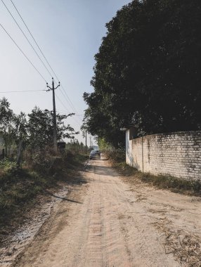 Feb15th2025 Dehradun Uttarakhand India. Sedan car leaving on a mud road in rural India, traveling countryside India. clipart