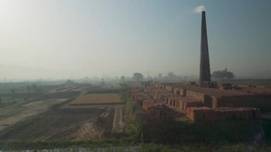 Landhaura, Roorkee, Hindistan 'da tarlaların arasında duman çıkaran tuğla ocağı. Endüstriyel manzara görüntüleri.