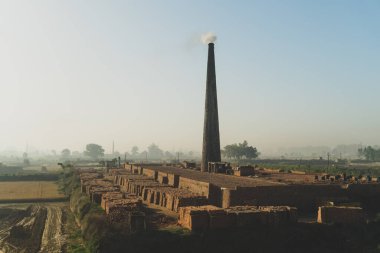 Landhaura, Roorkee, Hindistan 'da tarlaların arasında duman çıkaran tuğla ocağı. Endüstriyel manzara görüntüleri.