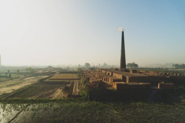Landhaura, Roorkee, Hindistan 'da tarlaların arasında duman çıkaran tuğla ocağı. Endüstriyel manzara görüntüleri.