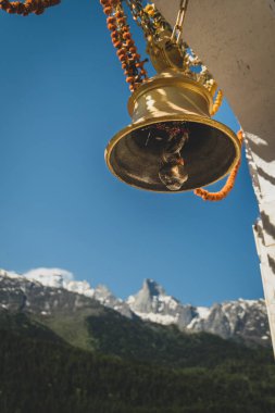 Uttarakhand, Harsil Vadisi 'ndeki bir köy tapınağından Gangotri Sıradağları' nın nefes kesici manzarası. Önünde bir tapınak çanı var..