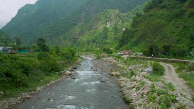 Muson mevsiminde Hindistan 'ın Dehradun, Uttarakhand kentinin sisli tepelerinden akan Serene Song Nehri canlı yeşillik ve dramatik Himalaya manzaralarıyla çevrilidir.